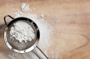 Powdered sugar being sifted using a screen.