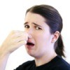 A woman holding her nose due to a rotten smell.