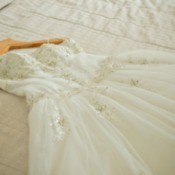 Wedding dress laid out on a bed.