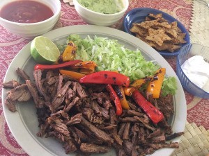 Skillet Carne Asada on plate with peppers lime and cabbage