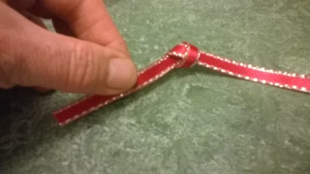 Tying a knot in the end of the ribbon.
