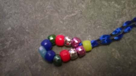 String a bead onto both strands of the ribbon and push down to the other beads.