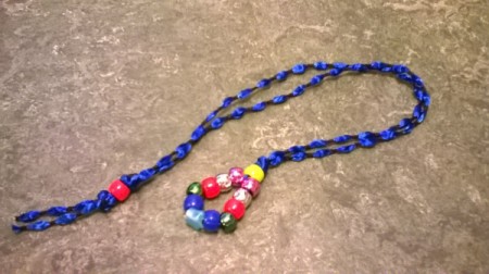 A completed bead and ribbon bookmark, with a blue ribbon and colored beads.