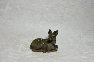 A small fawn figurine on a textured white piece of wallpaper.