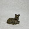 A small fawn figurine on a textured white piece of wallpaper.