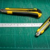 Green cutting mat with a ruler and two cutting tools.