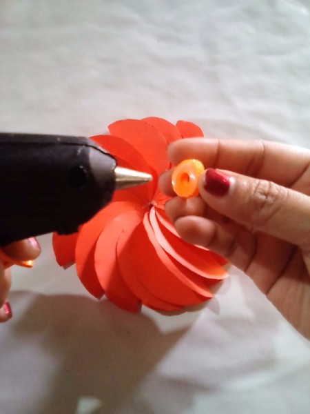 Making Folded Circle Paper Flowers - use hot glue to attach the button to the center of the flower