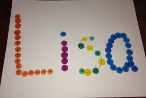 A piece of paper with the name "Lisa" marked in dots with colored bingo markers.