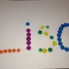 A piece of paper with the name "Lisa" marked in dots with colored bingo markers.