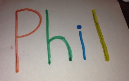 A piece of paper with the name "Phil" written with colored bingo markers.