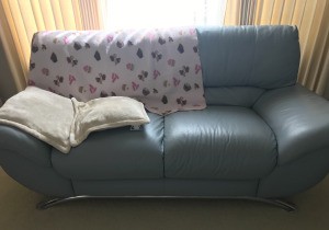 A leather couch with a blanket protecting from sun damage.