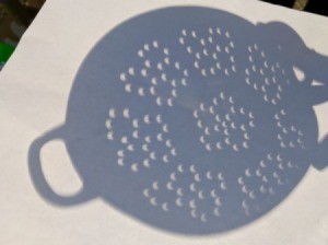A colander showing crescent moon shaped shadows on a light surface, from the solar eclipse.