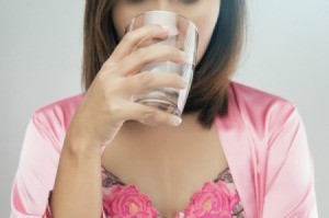 A woman with a glass of salt water preparing to gargle.