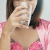 A woman with a glass of salt water preparing to gargle.