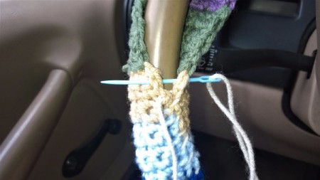 Attaching the crocheted cover to the steering wheel.