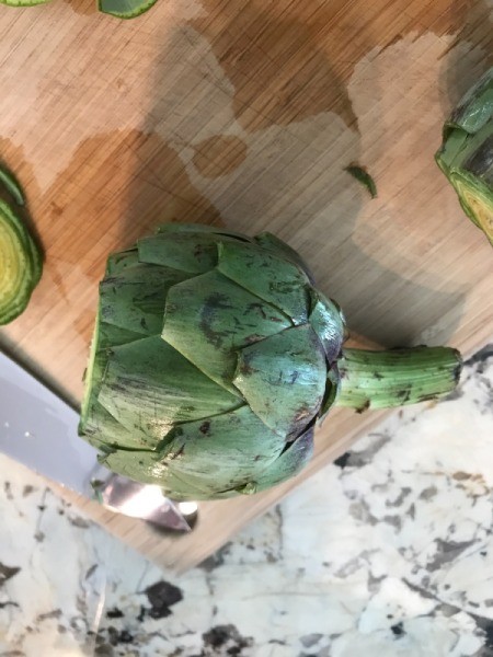 Cutting the end off the artichoke, in preparation for grilling.
