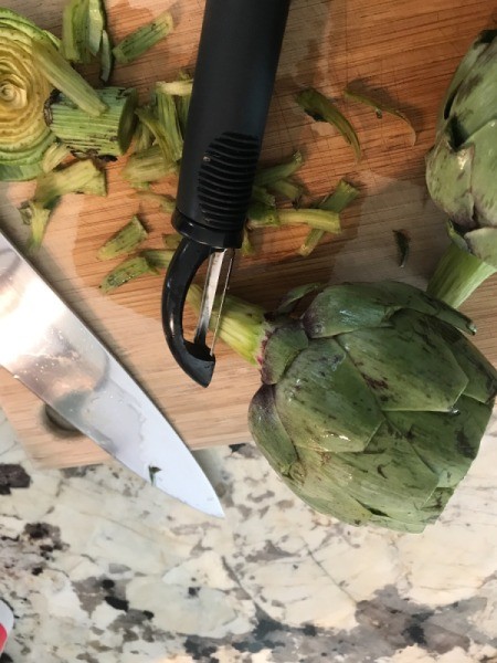 Peeling the stem of an artichoke.