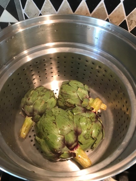 Artichokes cooked prior to being grilled over charcoal.