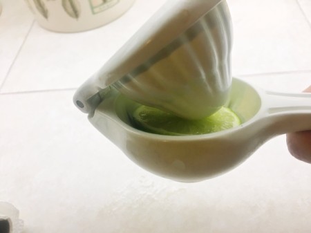 A citrus juicer being used on a lime section.