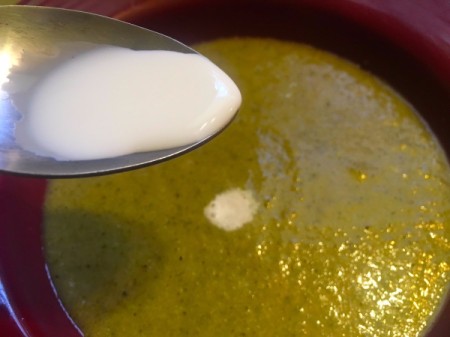 Adding a touch of cream to the finished bowl of soup, before serving.