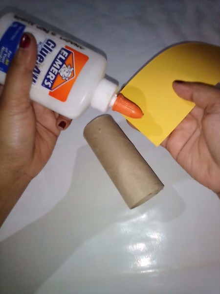 Adding glue to paper strip to glue to TP tube.