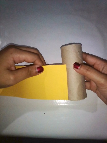 Gluing paper to an empty toilet paper tube to make the ninja's body.