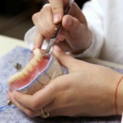 A person creating a denture plate.