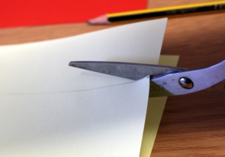 Cutting white paper into a strip.