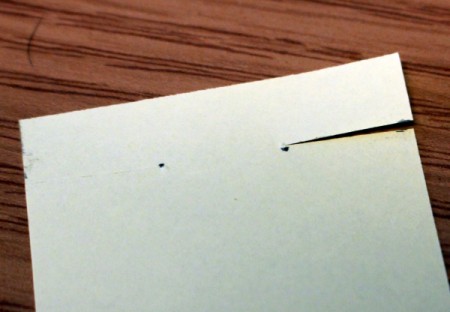 Cutting a slit to the mark on a piece of white paper.