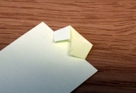 Folding the edges inwards to make the paper resemble a collared shirt.