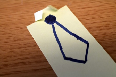 Drawing a tie below the collar fold on the white paper.