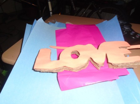 'Love' Cardboard Sign - stack of the four words "love" glued together
