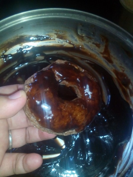 dipping donut in glaze