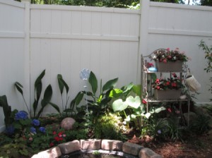 Using A Baker's Rack In Your Garden - rack near fence in garden