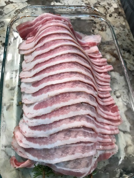 Bacon Wrapped Porchetta bacon laid on tenderloin in baking dish