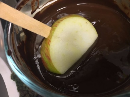 dipping Apple Slice Pops in chocolate