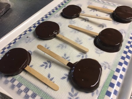 chocolate covered Apple Slice Pops  on parchment paper