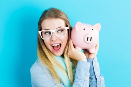 A woman holding a pink piggy bank.