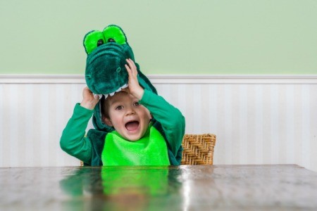 A cute kid wearing a crocodile costume.