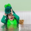 A cute kid wearing a crocodile costume.