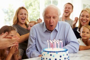 A grandfather blowing out candles at this birthday party.