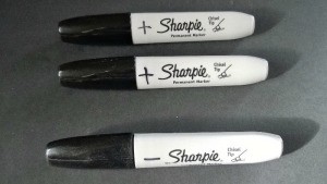 Large black Sharpie brand markers, with a plus or minus drawn on them.