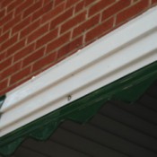 A clean section of gutter under a brick wall.