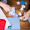 A girl making a homemade Christmas card with stickers and cutouts.