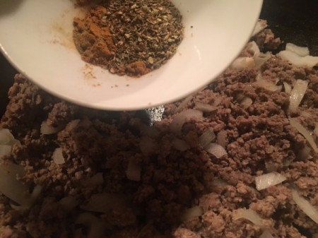adding herbs to ground beef and onions