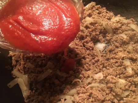 adding tomato sauce to ground beef mixture