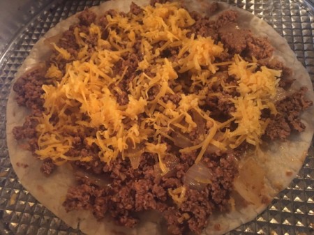 adding cheese to tortilla with ground beef mixture
