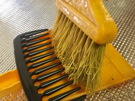 DIY Comb-top Dustpan - large tooth comb on dust pan with broom in place to clean