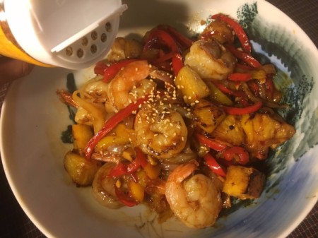 adding sesame seeds to Pineapple Pepper Prawns