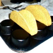 A muffin tin holding taco shells for filling.
